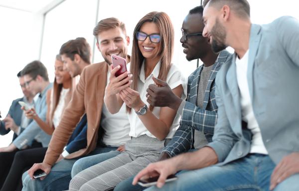 group of workers smiling while looking at a mobile phone