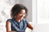woman with glassed smiling looking at laptop